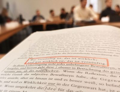 Im Vordergrund aufgeschlagene Seite aus Hegels Rechtsphilosophie, im Hintergrund Seminarteilnehmer